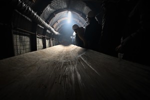 Zdjęcie przedstawia grupę osób w białych hełmach w korytarzach imitujących wnętrze kopalni