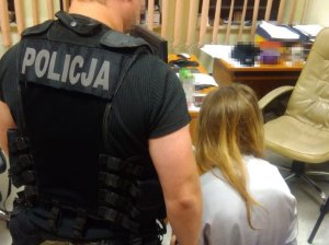 Policjant stoi przy zatrzymanej kobiecie