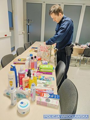 Policjant pakuje kosmetyki do torby papierowej