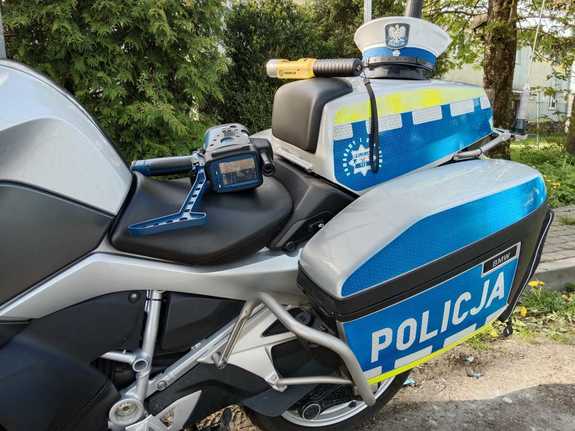 leżący na siedzisku motocykla miernik prędkości, na kufrze alkomat i czapka policjanta ruchu drogowego