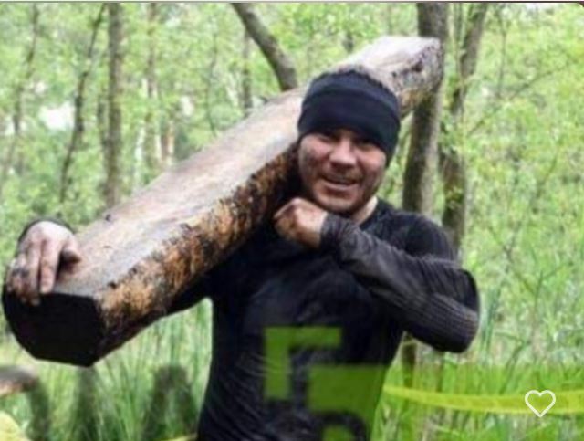 mężczyzna trzyma drewnianą dużą belę na ramieniu