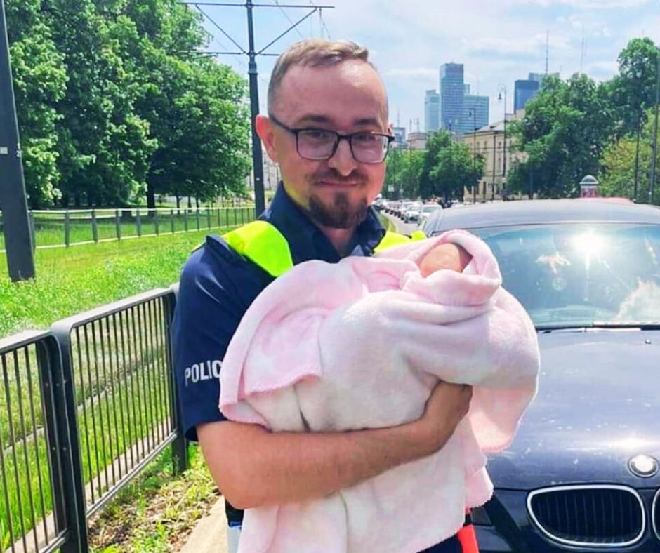 umundurowany policjant trzyma na rękach niemowlę w kocyku