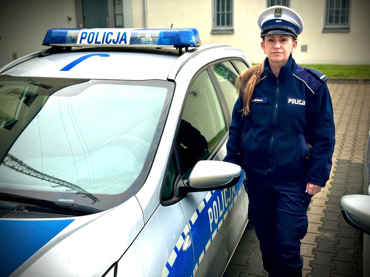 Policjantka stoi przy radiowozie.