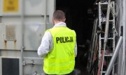 Policjant stoi przed kontenerem ze skradzionymi rzeczami