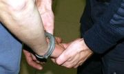 Policjant zakuwa zatrzymanego w kajdani - widoczne są tylko ręce