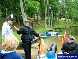 policjanci na łodzi sprawdzają trzeźwość osób wypoczywających nad wodą