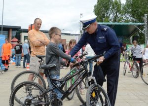Policjant drogówki objaśnia dziecku, jak powinien być wyposażony rower