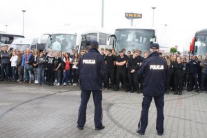 zdjęcie grupowe młodzieży i policjantów, w tle autobusy