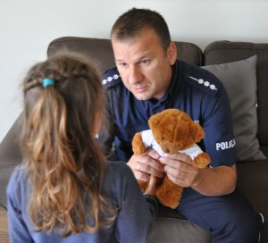 policjant przekazuje misia dziecku
