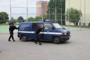radiowóz na boisku szkoły, policjanci stoją przy samochodzie