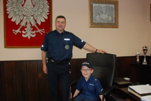 chłopiec na fotelu komendanta miejskiego Policji w Kaszliszu, obok stoi młodszy inspektor Mirosław Ścisły  - komendant tej jednostki