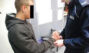 Policjant zakłada kajdanki zatrzymanemu - zdjęcie poglądowe