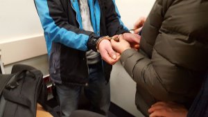 Policjant zakłada kajdanki zatrzymanemu