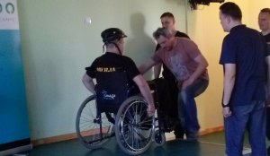 Pomoc kolegów przy poruszaniu się na wózku inwalidzkim
