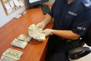 policjant liczy zabezpieczone pieniądze