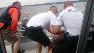 policjanci podejmują żeglarzy z wody