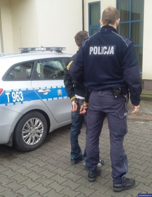 policjant prowadzi zatrzymanego