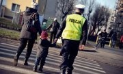 policjant razem z kobietą przeprowadza dziecko przez jezdnie