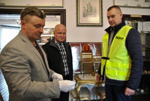 policjant przekazuje odzyskany zabytkowy sygnet rodzinny pierwszego niepodległościowego Burmistrza Mińska Mazowieckiego