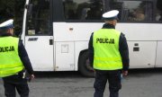 dwaj policjanci z drogówki przystępują do kontroli białego autokaru