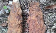 odnalezione niewybuchy - dwa pociski artyleryjskie leżące na leśnej ściółce pokryte rudą rdzą