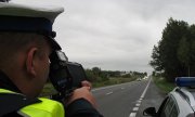 Policjant przy drodze dokonuje pomiaru prędkości