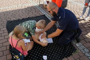 policjant  przy fantomie pokazuje dzieciom jak udzielać pierwszej pomocy