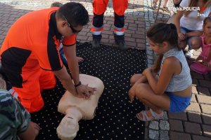 ratownik przy fantomie pokazuje dzieciom jak udzielać pierwszej pomocy
