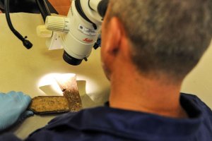 laborant ogląda ostrze siekiery przez mikroskop