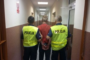 zatrzymanego mężczyznę odprowadzają dwaj policjanci