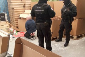 Funkcjonariusze Służby Celno-Skarbowej, w tle zatrzymany i krajanka tytoniowa
