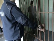 policjant zamyka celę dla zatrzymanych