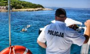 Policjant nakłada mandat za pływanie w niedozwolonym miejscu na szlaku wodnym