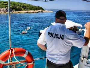 Policjant nakłada mandat za pływanie w niedozwolonym miejscu na szlaku wodnym