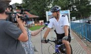 policjant na rowerze udziela wywiadu dziennikarzom