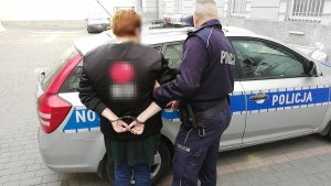 zatrzymana kobieta prowadzona przez policjanta do radiowozu