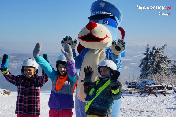 Policyjna maskotka stoi na stoku wspólnie z dziećmi.