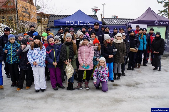 Policjanci wspólnie z dziećmi stoją na stoku.