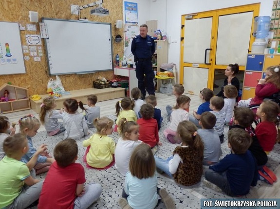 Policjant przekazuje zasady bezpiecznego zachowania na stoku narciarskim.