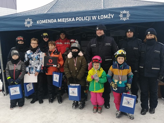 Na stoku narciarskim stoją dzieci wspólnie z policjantami.