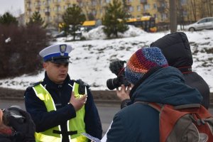 policjant z kamerą przyczepioną do munduru udziela wywiadu dziennikarzom