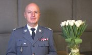 Komendant Główny Policji, obok kwiaty w wazonie.