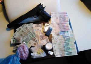 Pieniądze, żółte i różowe tabletki w woreczkach, przedmiot przypominający broń zabezpieczone przez policjantów