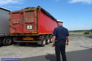 Policjant ruchu drogowego stojący przy kontrolowanej naczepie ciężarówki