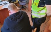 zatrzymany przez policjantów diler narkotyków siedzi przy biurku podczas przesłuchania