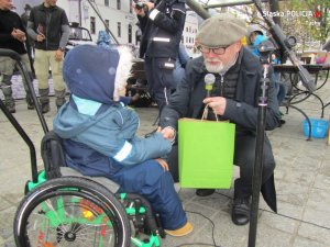 Obrazek przedstawia Burmistrza Miasta Ustroń, który wręcza upominek 6-letniemu Jasiowi, który siedzi na wózku inwalidzkim