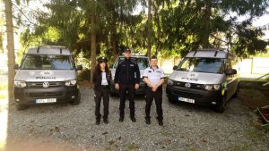 polski policjant w mundurze z policjantką i policjantem z Czech, w tle trzy radiowozy policyjne