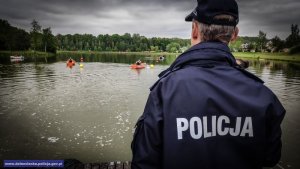 zawodnicy pływają łódkami, na pomoście stoi policjant