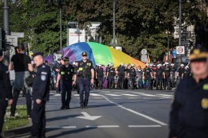ul. Piłsudskiego. Policjanci oddziału prewencji idą na czole „Marszu Równości” za nimi tłum i flaga ruchu LGBT.