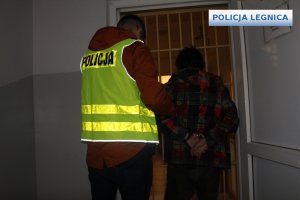 Policjant z zatrzymanym przed wejściem do pomieszczeni dozorowanego